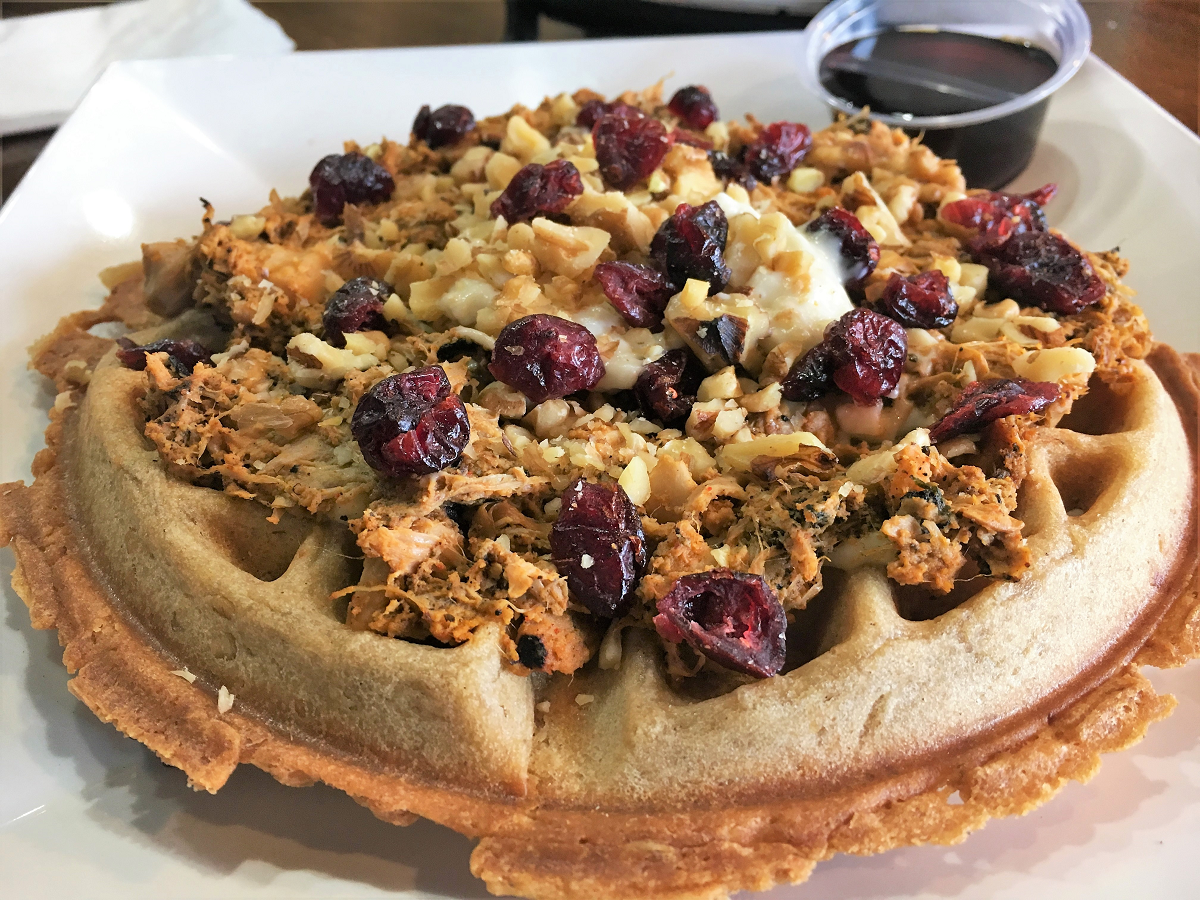 vegan waffle topped with jackfruit shredded chicken, cranberries, and nuts